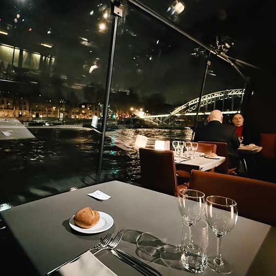 Cenar en el río Sena de París con la ciudad iluminada.